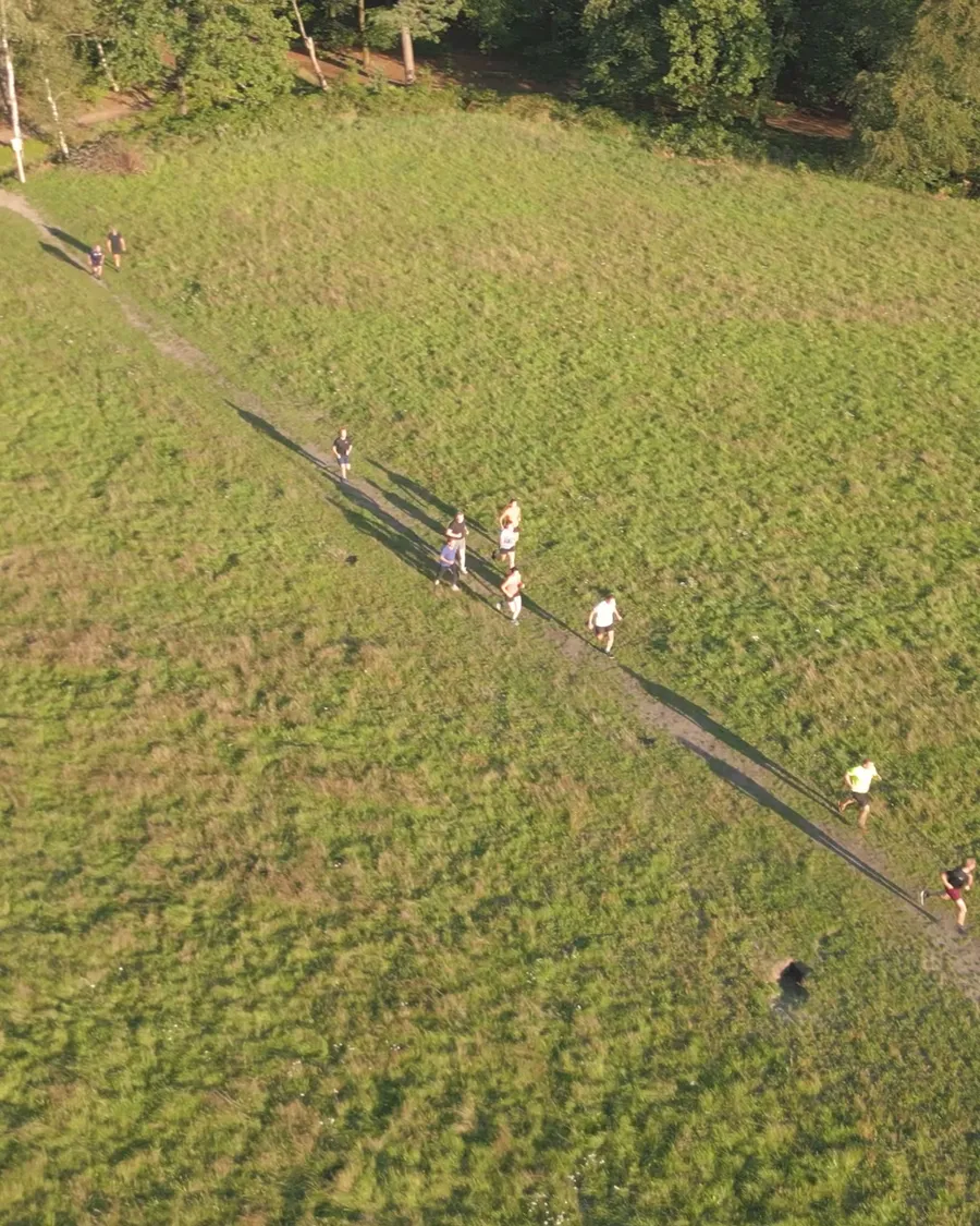 Luchtopname groep hardlopers bij bootcamp op de Heuvelrug, gouden avondlicht